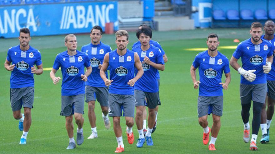 Un grupo de futbolistas del Deportivo trota sobre el césped.