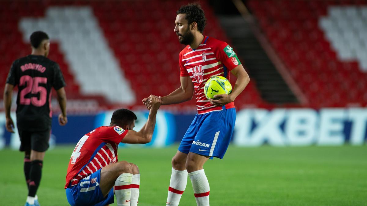 Germán Sánchez ayuda a levantarse a Fede Vico en un partido del Granada.