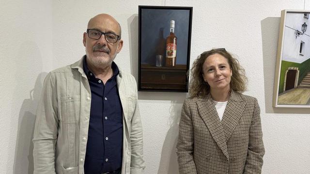 Emilio Balduque y Cristina Serrano, junto al cuadro de la botella de licor de guindas Los Serranos.