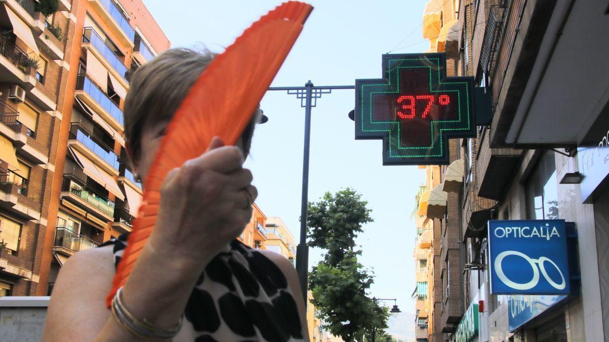 Una mujer se abanica junto a un termómetro durante la cuarta ola de calor del verano.