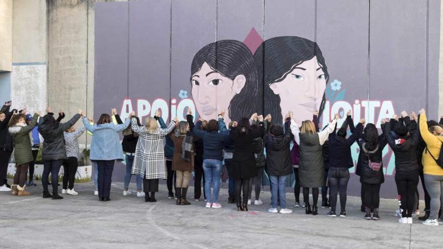 Las internas junto con representantes institucionales posan ante el graffiti realizado en el centro penitenciario