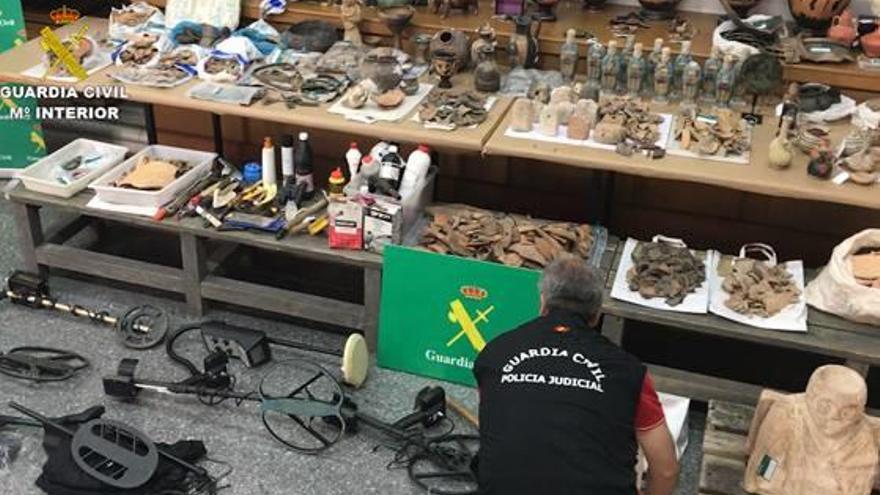 Un guardia civil junto a las piezas arqueológicas intervenidas en la operación.