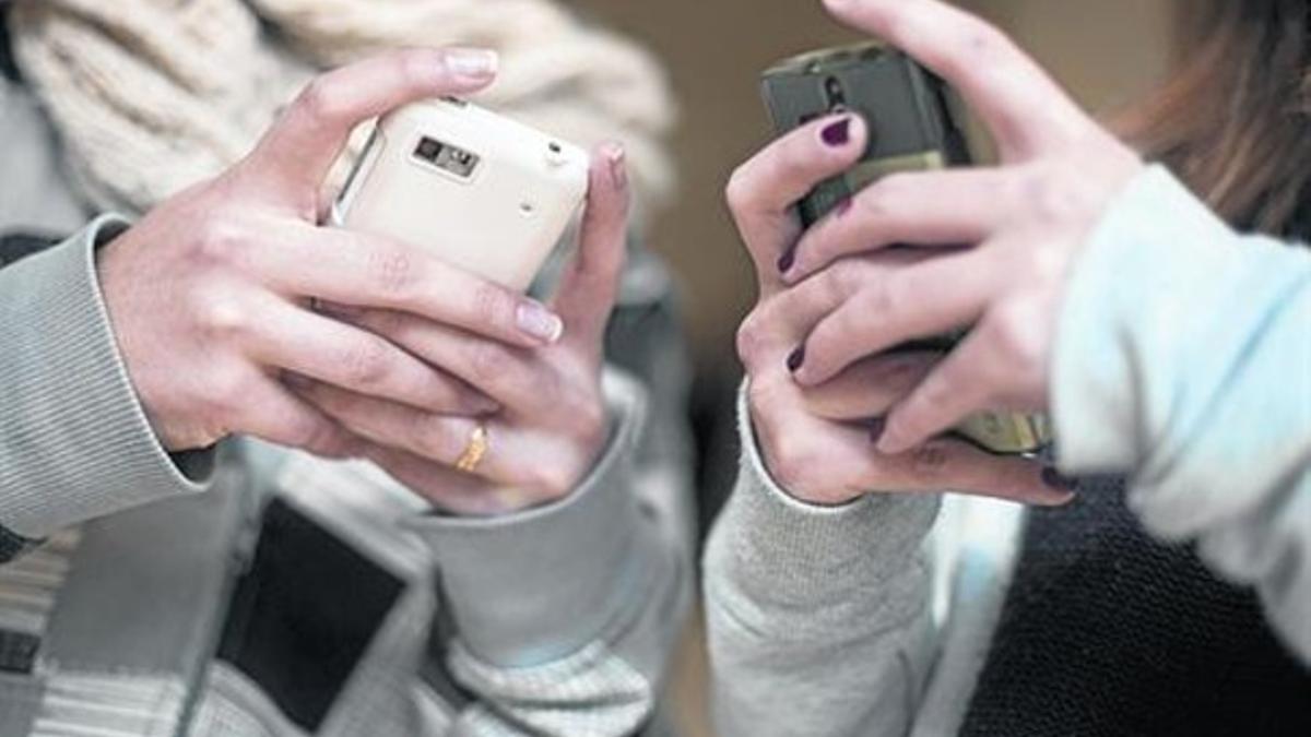 Usuarios 8 Dos estudiantes usan sus teléfonos móviles.