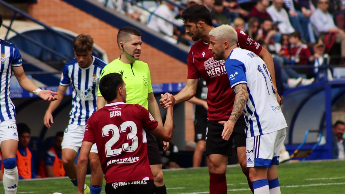 Busi y Bourdal, junto al colegiado y un jugador del Recreativo de Huelva.