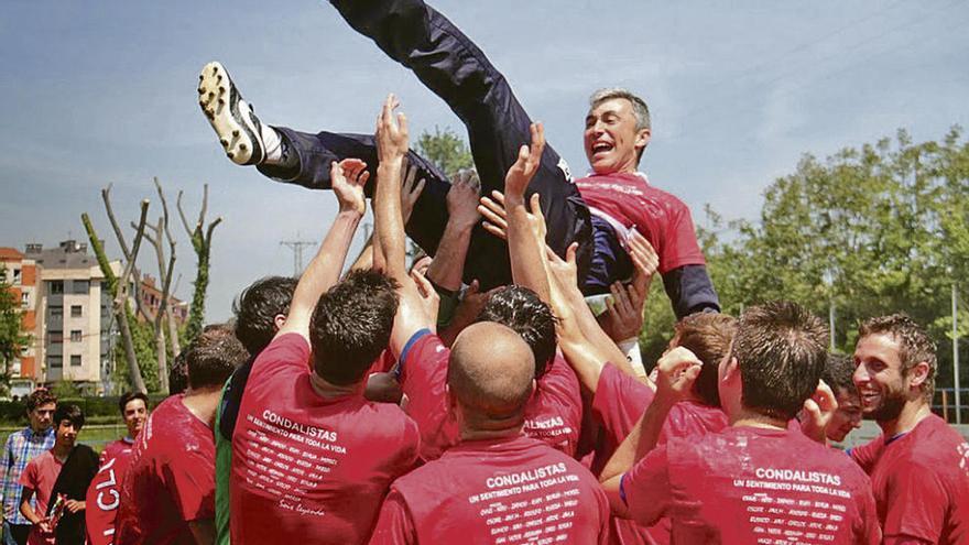 La plantilla del Condal mantea a Jaime Leiva tras asegurar el liderato de la Tercera asturiana.