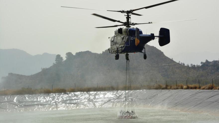 Un helicóptero recoge agua de una balsa de riego