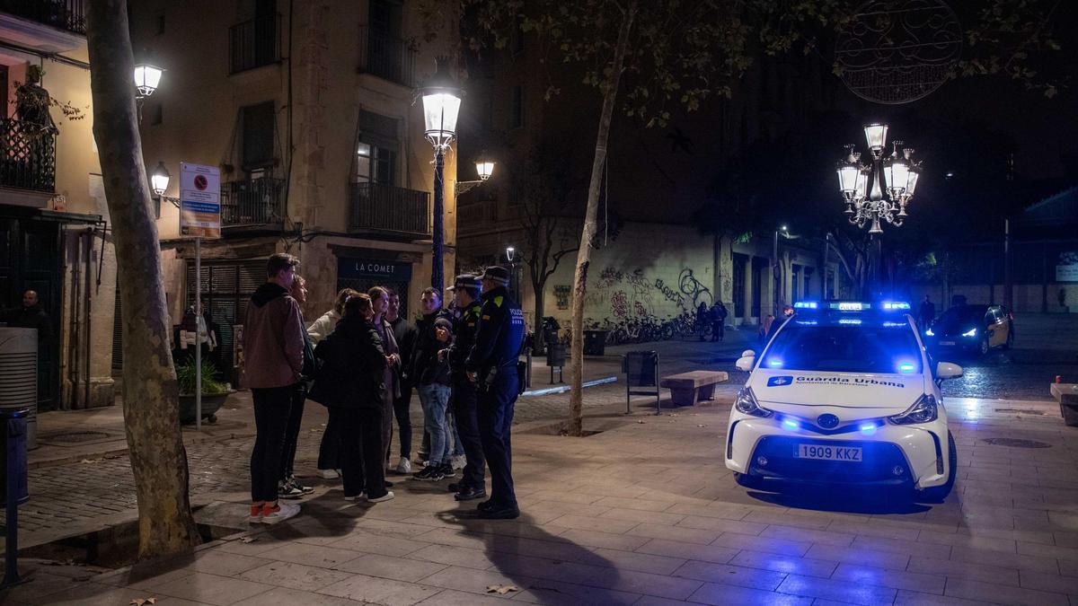 Agentes de la Guardia Urbana informan a los viandantes de la entrada en vigor del toque de queda.