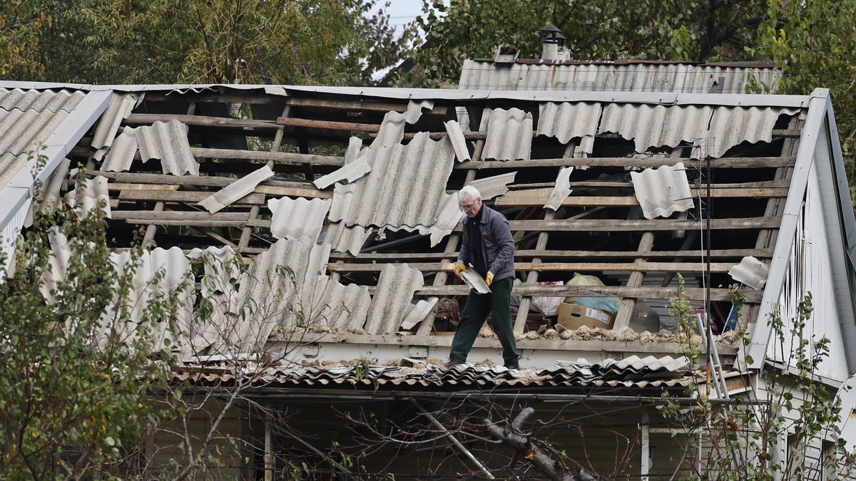 Un ciudadano intenta recoger piezas de un techo destrozado en una ciudad de Ucrania