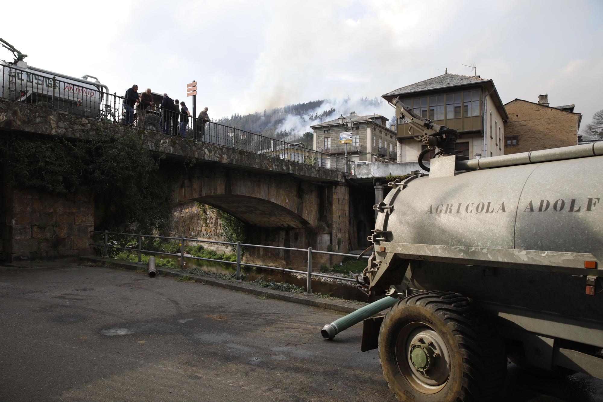 Agricultores ayudando en la extinción de los focos de fuego y enfriando las inmediaciones de la gasolinera de Navelgas