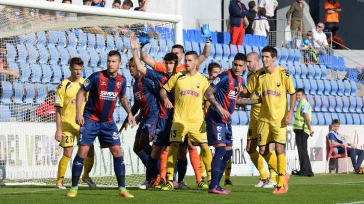 Los jugadores del Reus y del Huesca pugnan en el lanzamiento de un córner.