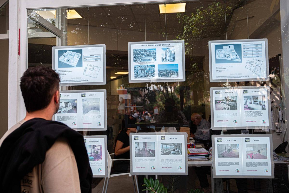 Personas viendo el escaparate de una inmobiliaria en Vigo.