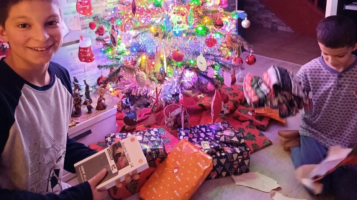 Enol y Noel Álvarez Pascual abren sus regalos bajo el árbol.