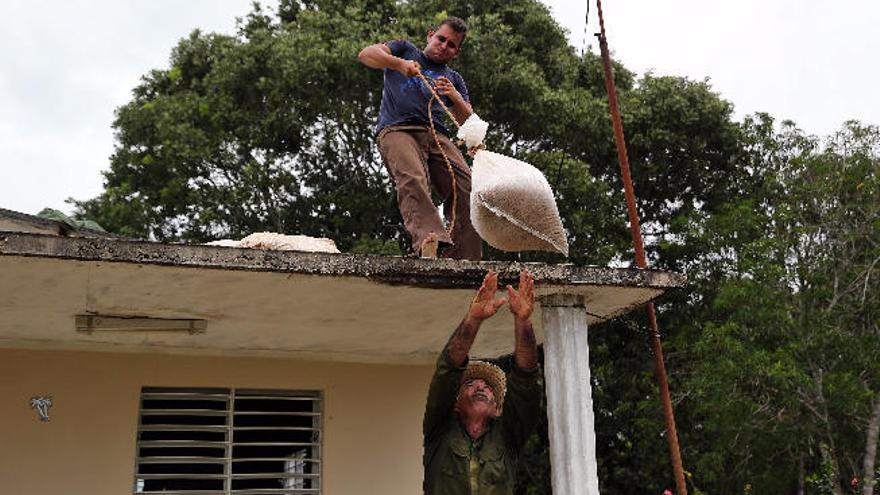 Dos hombres refuerzan el techo de una casa en Turiguanó, en Cuba.