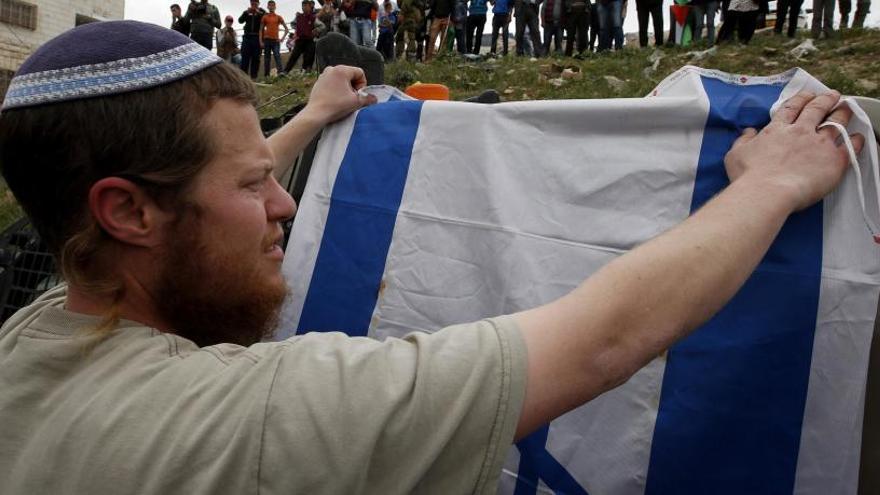 Un colono judío muestra la bandera nacional en Hebrón.