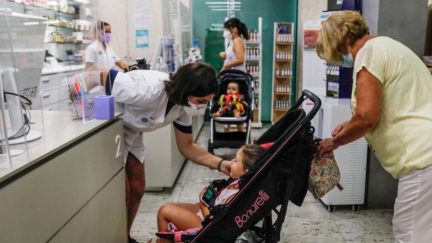 Una farmacéutica atiende a unos clientes en una farmacia de Ibiza. | ZOWY VOETEN