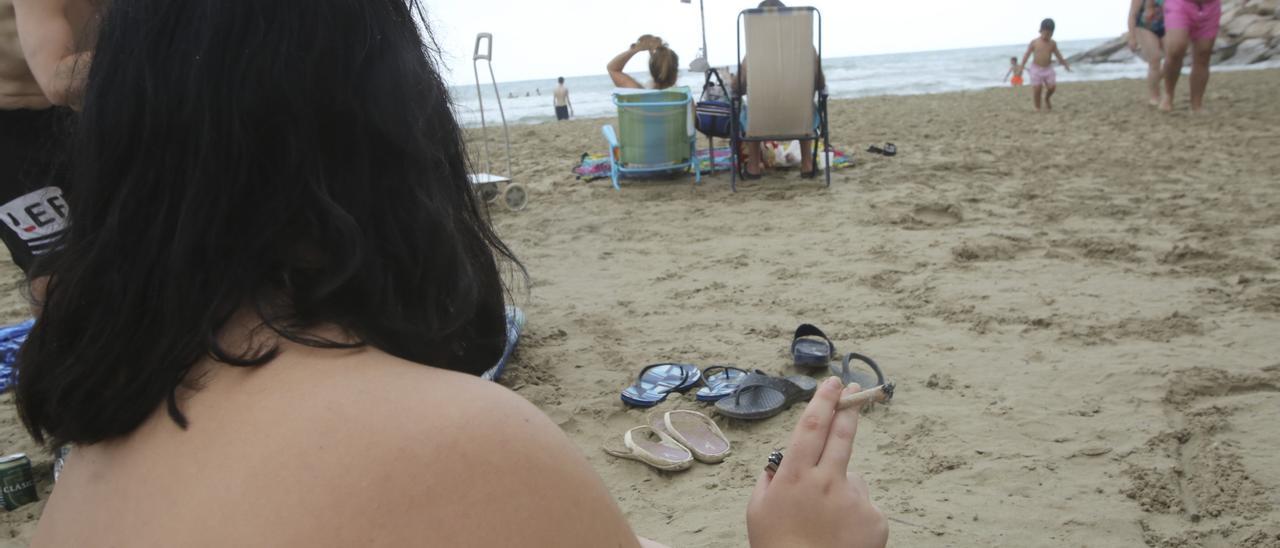 Una bañista fuma un cigarro en la playa de El Postiguet de Alicante, uno de los arenales declarados libres de humo dentro de la red de concienciación de Sanidad. | PILAR CORTÉS