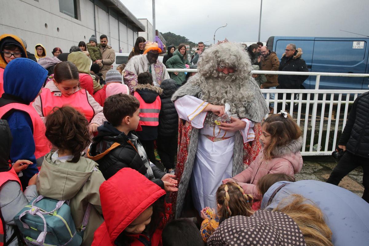 Uno de los reyes reparte caramelos a los niños en el muelle.