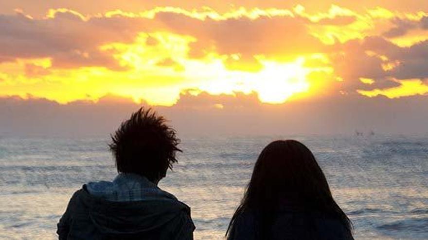 Una pareja observa una puesta de sol.