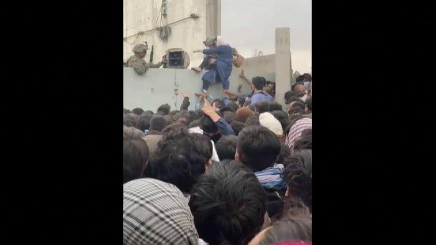 Soldados estadounidenses ayudan a una mujer afgana a saltar el muro del aeropuerto de Kabul.