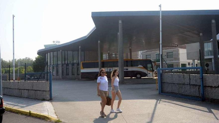 Dos mujeres caminan frente a la estación de autobuses de Cambados, con un solo autocar. // Noé Parga