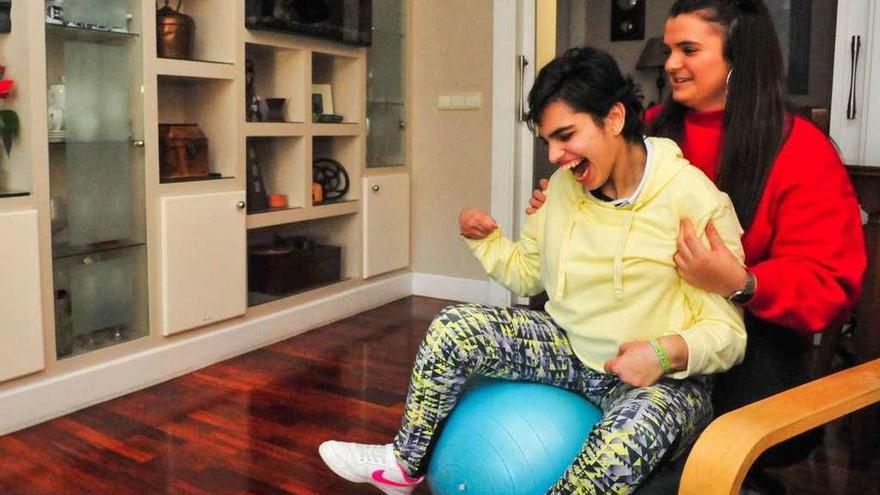 Paula y su hermana realizan ejercicios de rehabilitación en el salón de su casa de Vilagarcía. // Iñaki Abella