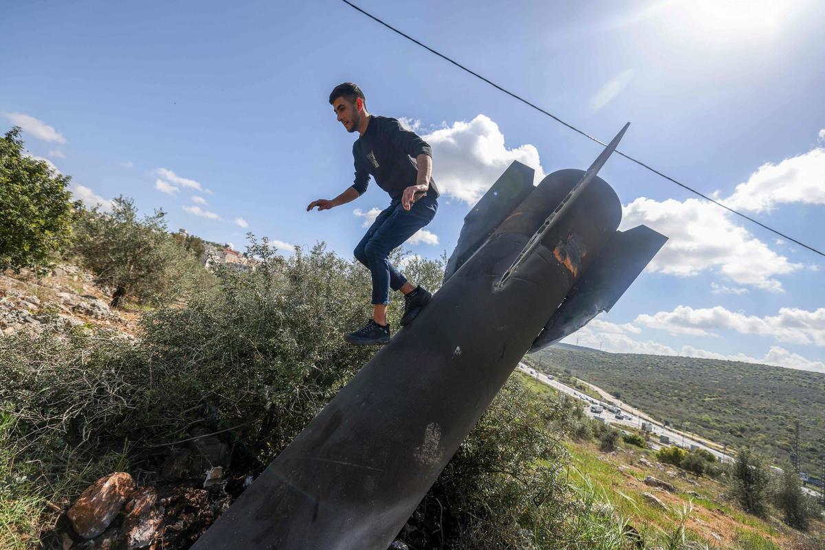 Un hombre palestino salta sobre los restos de un misil iraní en el pueblo de Hares, Cisjordania, el 24 de marzo de 2026. La guerra en Oriente Medio se ha intensificado tras los ataques de EE. UU. e Israel a Irán