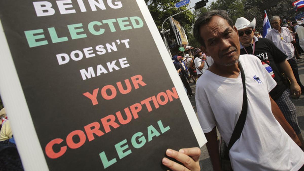 Un tailandés lleva una pancarta con un mensaje al Gobierno: &quot;Haber sido elegido no hace tu corrupción legal&quot;, este lunes durante las manifestaciones en Bangkok.
