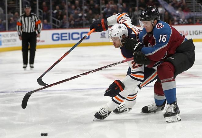 Leon Draisaitl de los Edmonton Oilers lucha por el control del disco contra Nikita Zadorov de la Colorado Avalanche en el primer período en Pepsi Center, en Denver, Colorado.