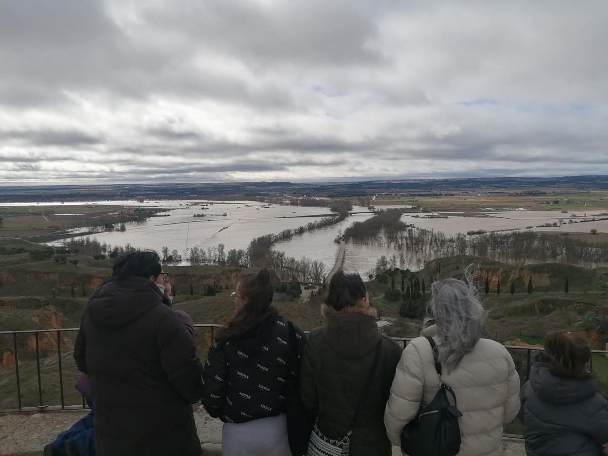 Varias personas admiran desde el Espolón la crecida del Duero este lunes.
