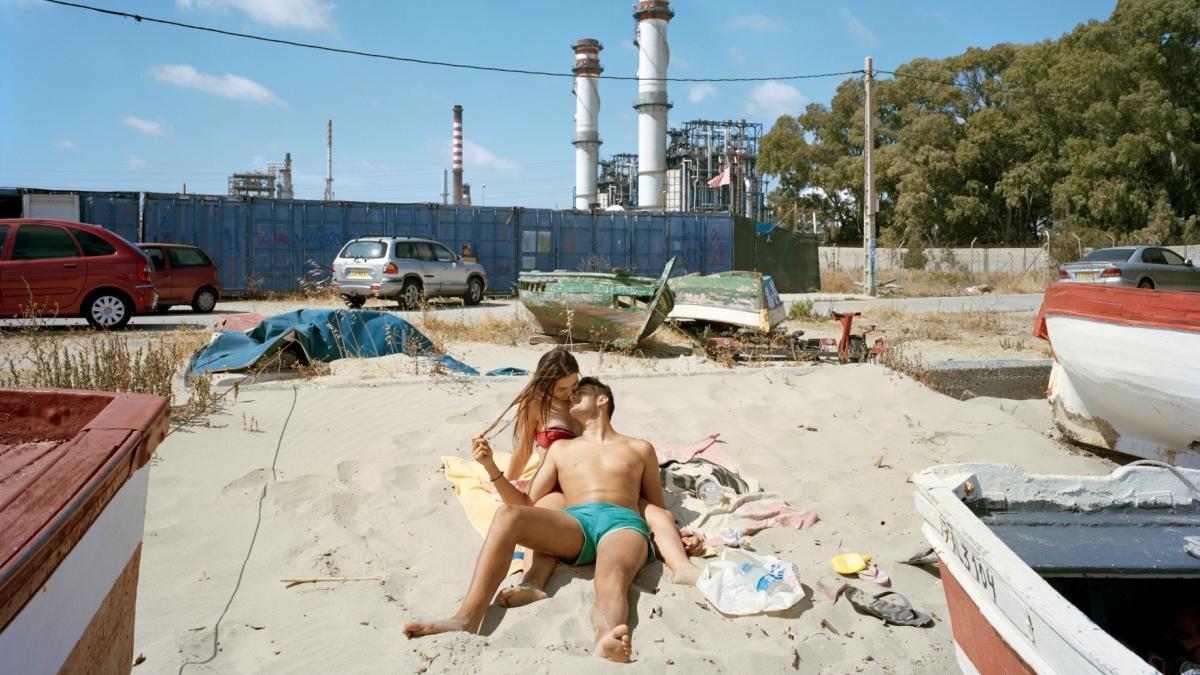 El romanticismo de la pareja en 'San Roque' contrasta con la fábrica del fondo.