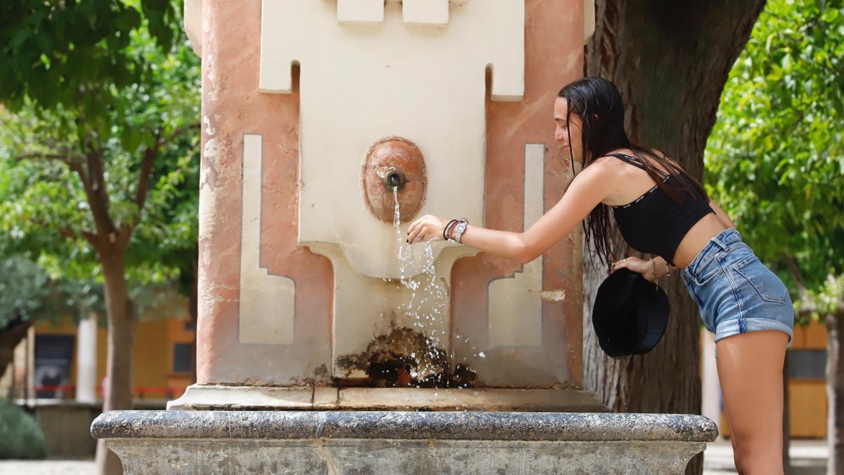 Una mujer se refresca en una fuente.
