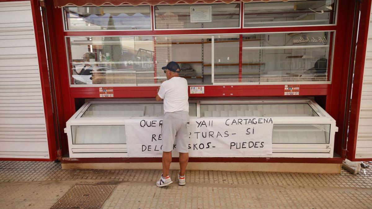 Un hombre se acerca a un quiosco con una pancarta para que les dejen ampliar su negocio. IVÁN URQUÍZAR