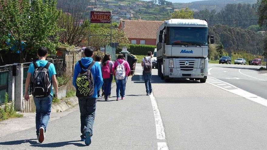 Unos niños caminan por el arcén de la N-550 hacia el colegio Outeiro das Penas, en Cesantes.  // FdV