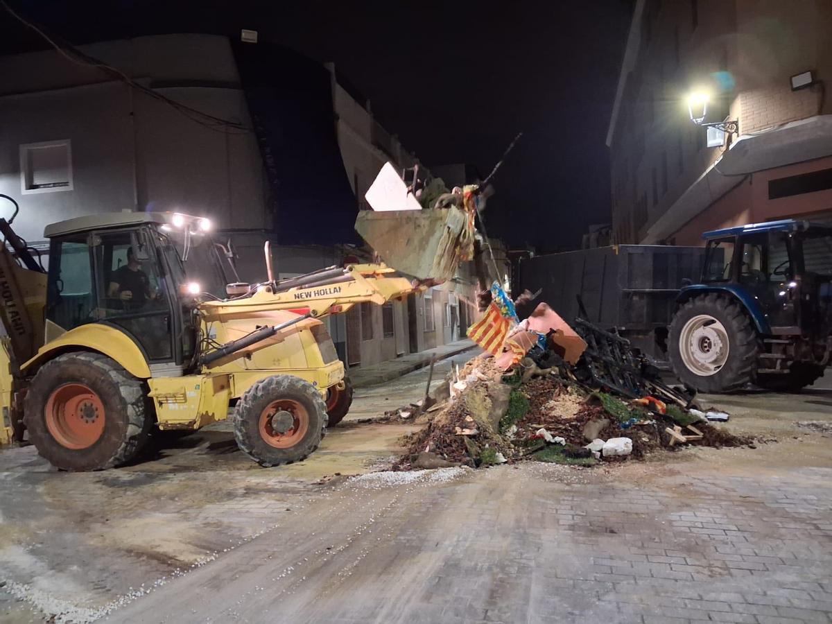 Una pala del servicio de limpieza trabaja en la retirada de los restos de una falla tras la "cremà".