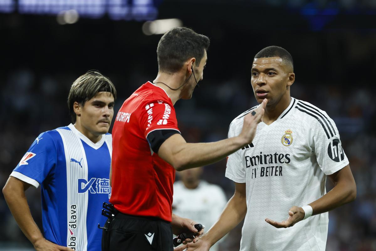 El colegiado Muñiz Ruiz y el delantero francés del Real Madrid, Kylian Mbappé, debaten durante el encuentro.