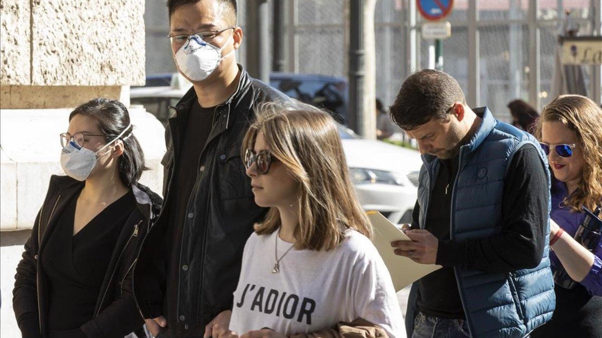 Personas con mascarilla ante el riesgo de coronavirus hacen cola ante la oficina del padrón del Ayuntamiento de Valencia