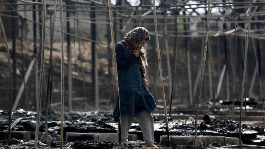 Una refugiada camina entre ruinas calcinadas del campo de Moria. // Efe