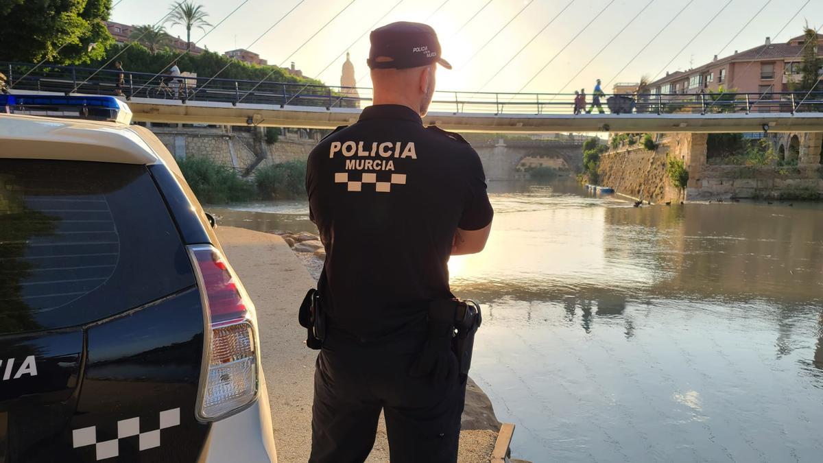 Un agente de la Policía Local de Murcia, junto a su vehículo.