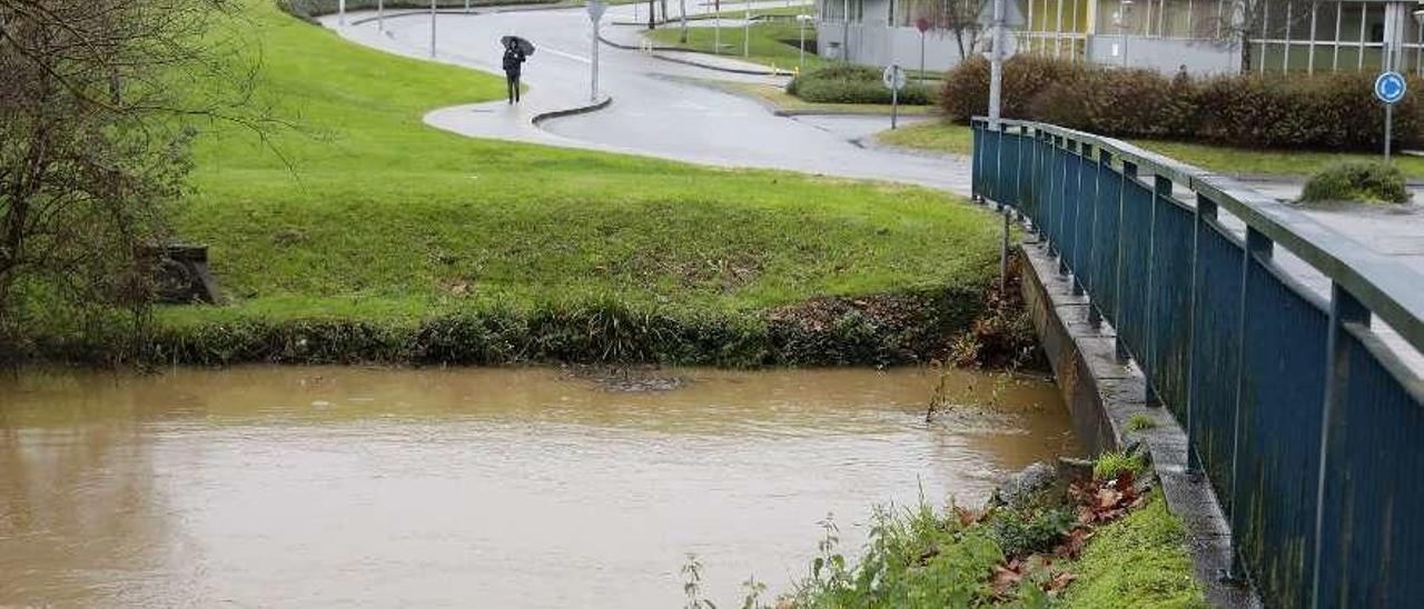 En primer término, un tramo del río Peñafrancia, con el edificio polivalente del campus de Gijón al fondo a la derecha de la imagen.