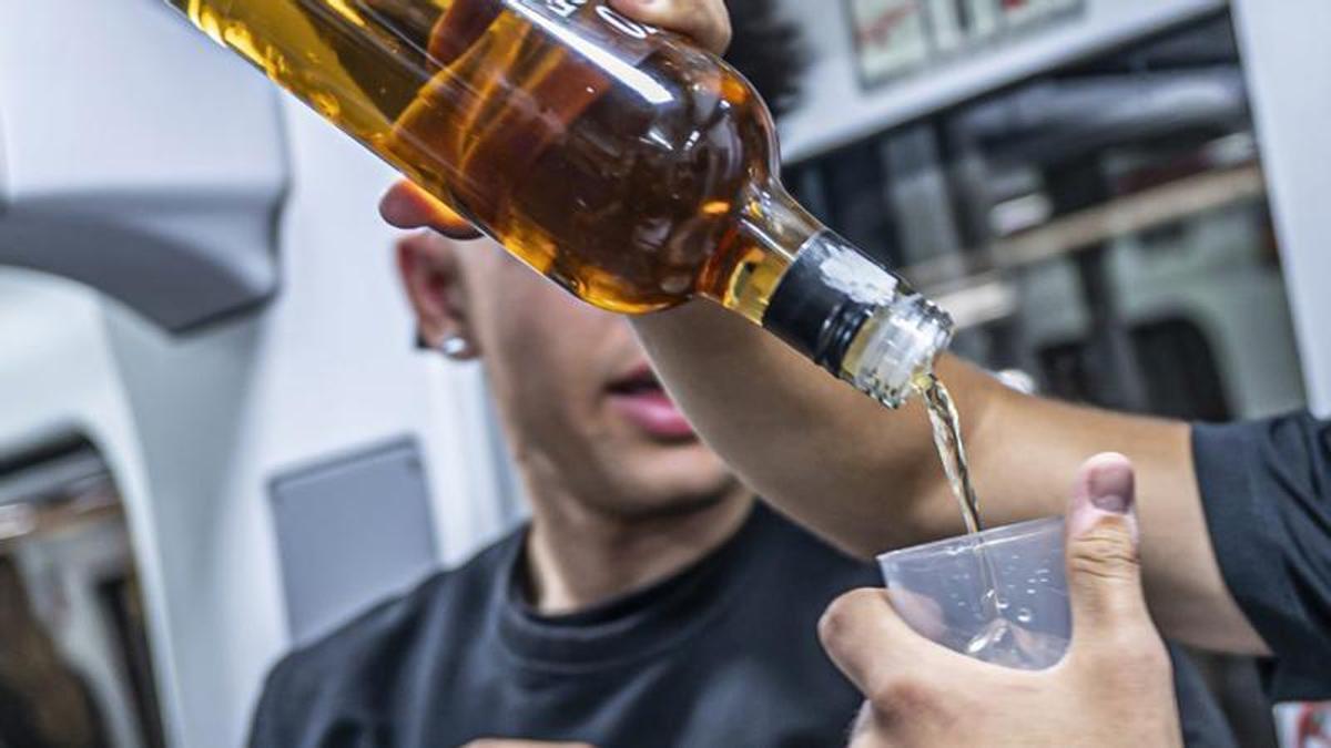 Un jove es posa alcohol al seu vas al metro de Barcelona.Un jove es llança alcohol al seu vas i un altre sosté una beguda energètica, al metro de Barcelona. | MANU MITRU