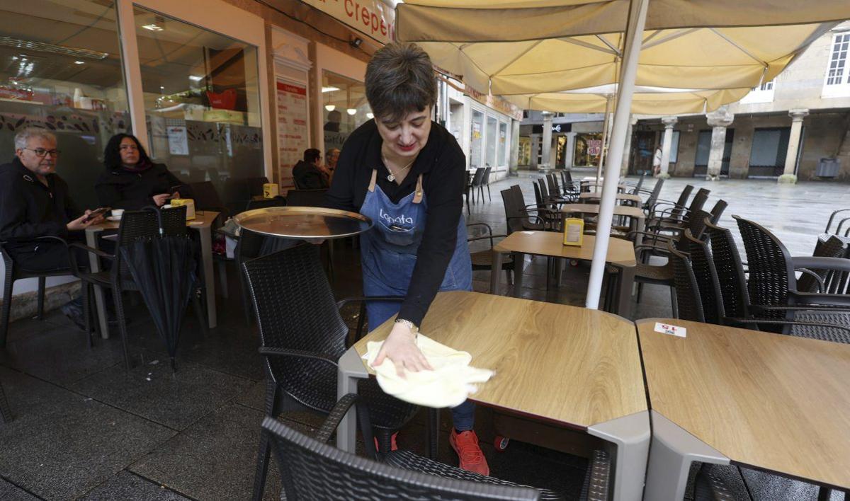 Una de las camareras de «La Nata» limpia una mesa en una terraza medio vacía. | GUSTAVO SANTOS