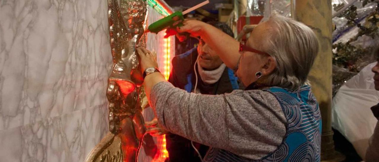 María Jesús Fernández decora una de las carrozas ante la atenta mirada de Javier Martínez.