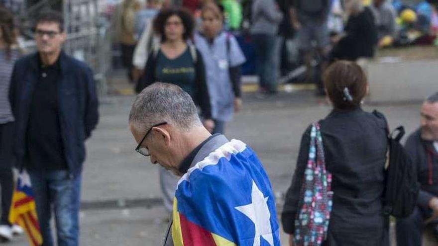 Un hombre mira su móvil cubierto con una estelada, ayer, en Barcelona, frente al Tribunal Superior de Justicia de Cataluña. // Efe