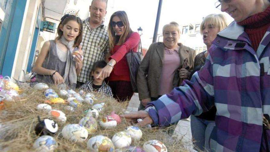 Varios vecinos observan un puesto de huevos pintos montado en la calle.