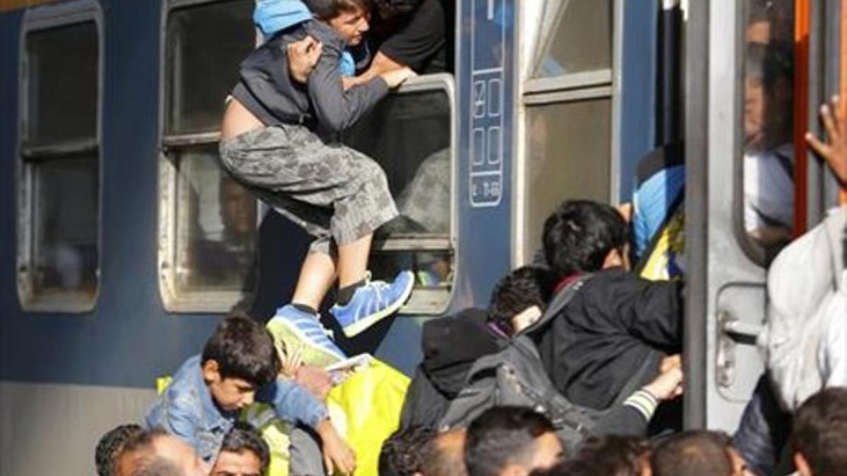 Unos refugiados intentan meter a un niño en un tren en Budapest, ayer.