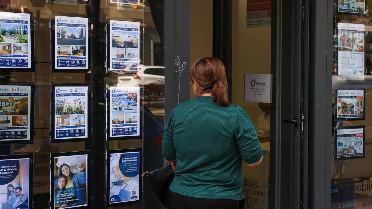 Una mujer, frente al escaparate de una inmobiliaria, en una imagen de archivo.