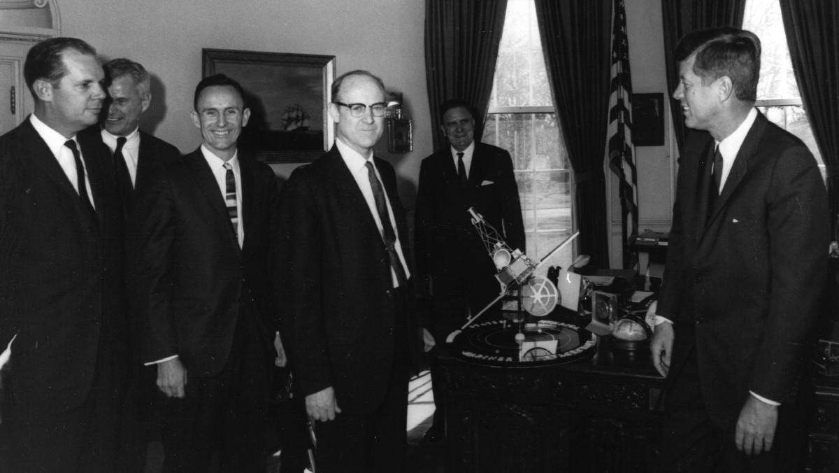 El presidente John F. Kennedy se reune con William H. Pickering (centro), director del Jet Propulsion Laboratory, y James Webb (detrás de la maqueta) para hablar hablar de las primeras misiones de la agencia.