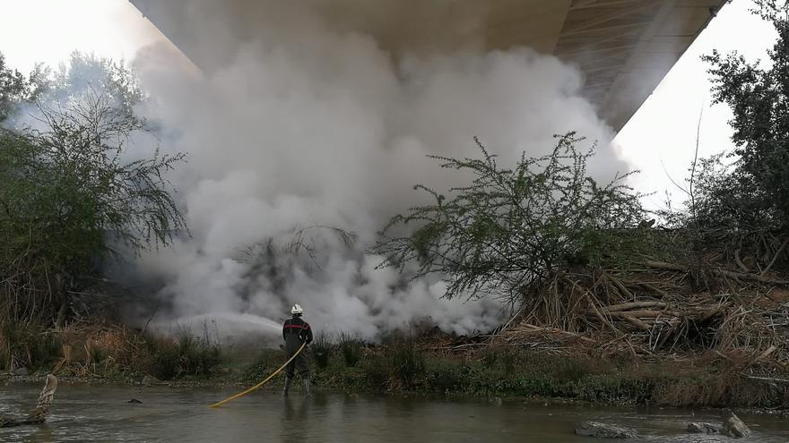 Los bomberos apagan un fuego en un islote bajo el puente Ibn Firnás