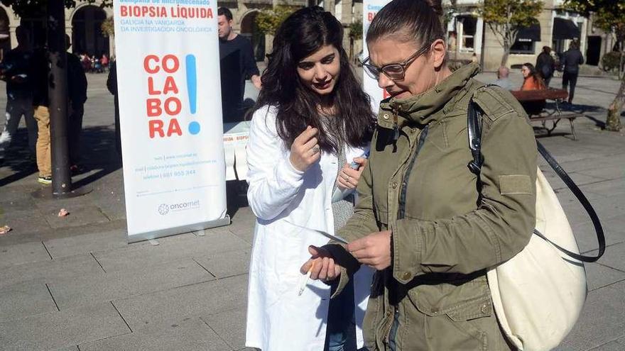 Una profesional de Oncomet entrega un folleto informativo, ayer, en A Ferrería. // Rafa Vázquez
