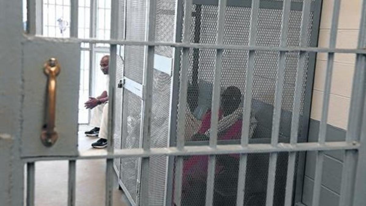 En la foto superior, dos presos esposados y con grilletes esperan a ser trasladados desde las dependencias de la prisión principal. Sobre estas líneas, el momento del recuento.
